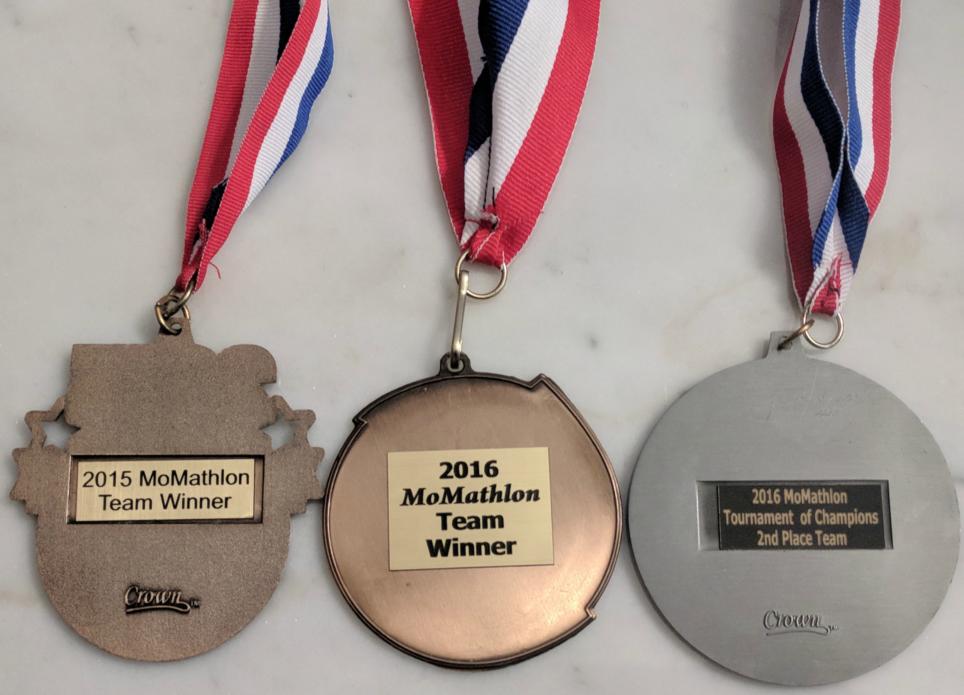 The backs of my MoMath competition medals