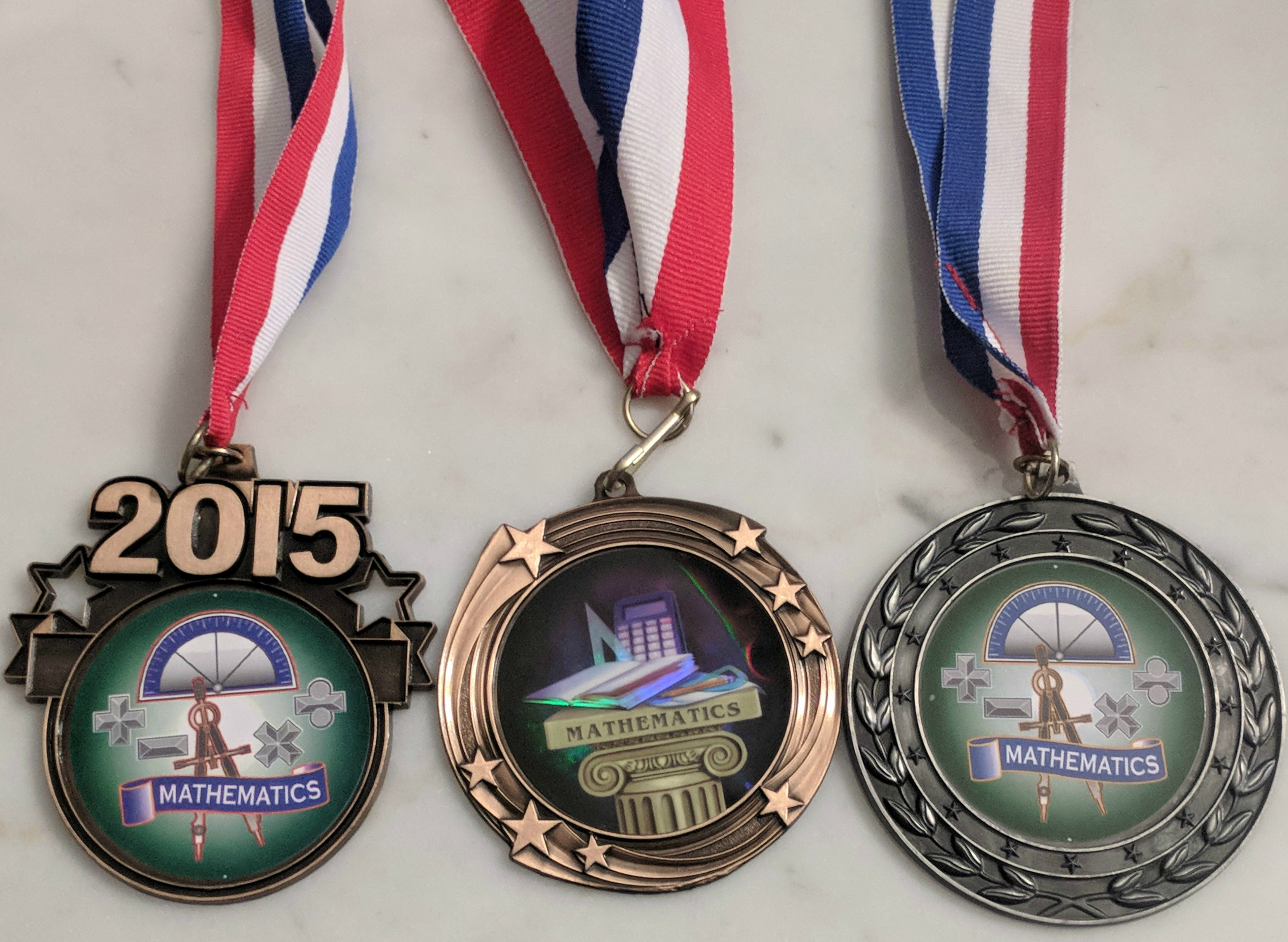 The fronts of my MoMath competition medals