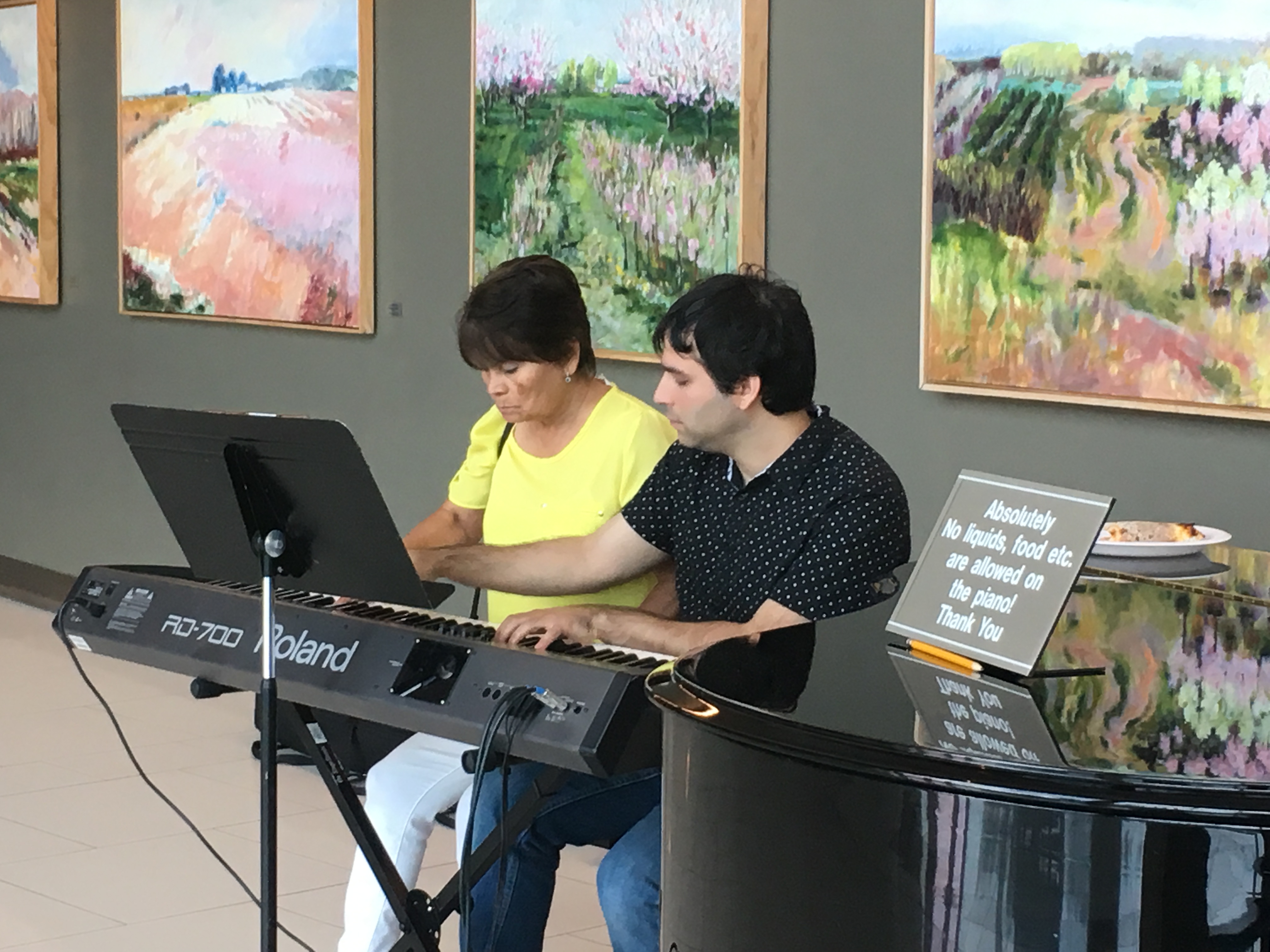 2 members of Piano for Patients playing a duet